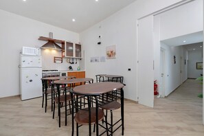 A compact kitchen with modern appliances, a dining area with four stools, and a hallway leading to another room. - Room 'Monster Room' (Sestu)