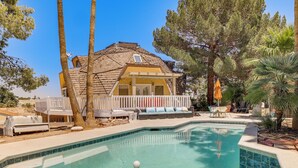 Una casa con piscina, terraza y un patio cercado con mobiliario exterior.