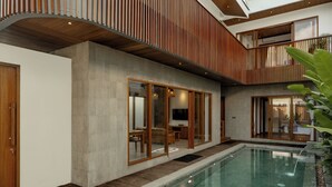 Ett modernt hus med en swimmingpool, ett trädäck och stora skjutbara glasdörrar.
