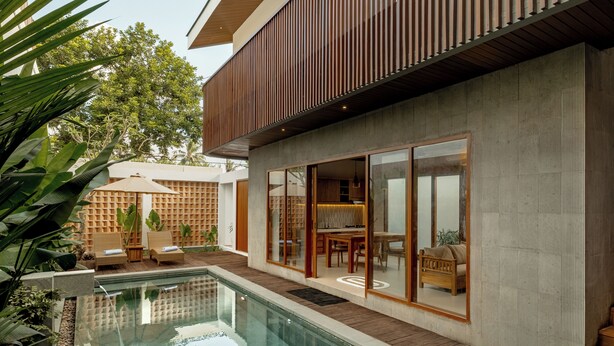 Ett modernt hus med en swimmingpool, ett trädäck och en matplats med utsikt över poolen.