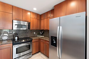 A kitchen with wooden cabinets, a stainless steel refrigerator, a microwave, an oven, and a coffee maker. - Golf Course Condo Near Beaches & Sunset Views -Kapalua Golf Villas 17P78 (Lahaina)