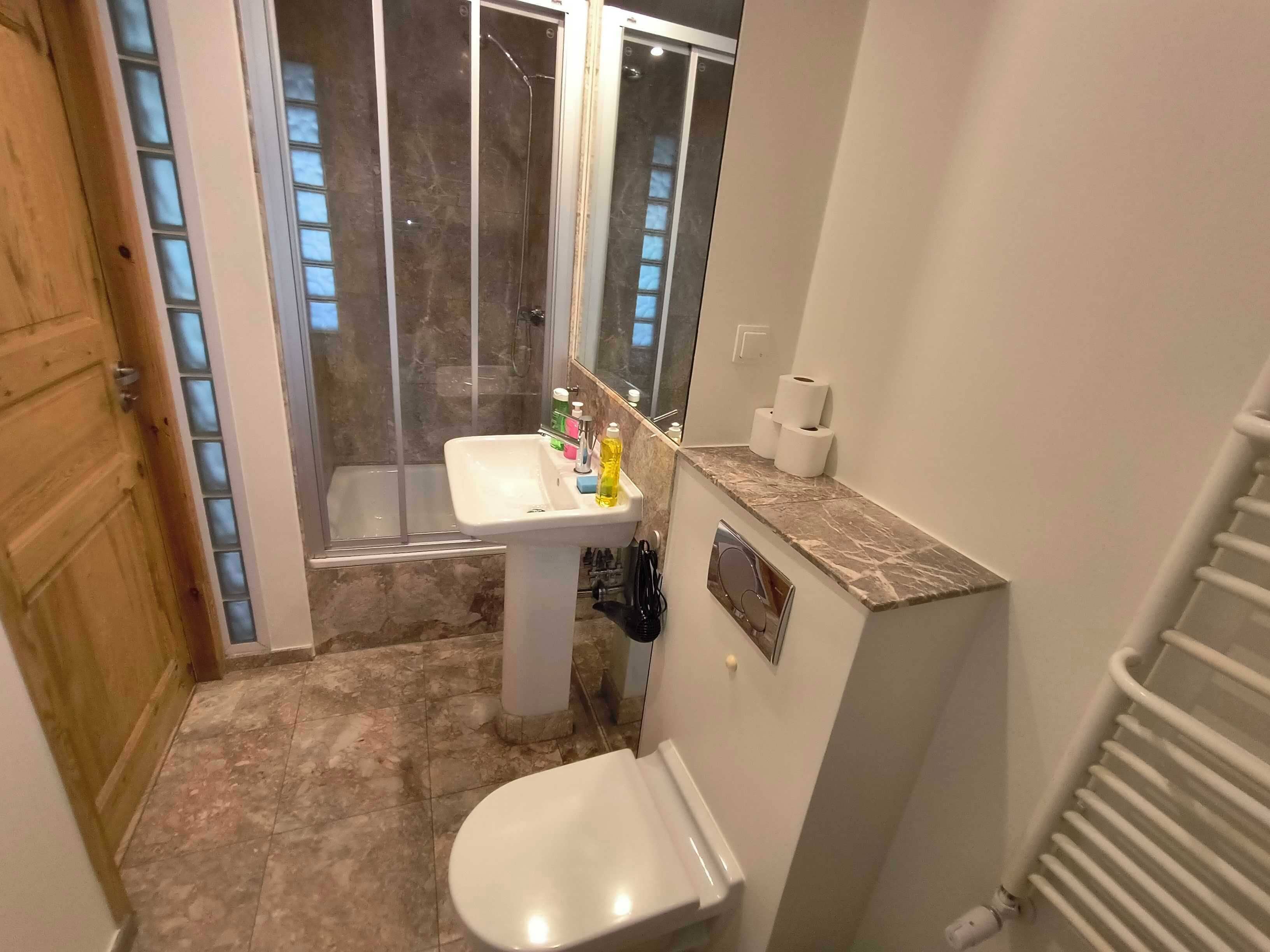 Un bagno con doccia, lavandino, WC e uno specchio.