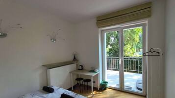 A bedroom with a bed, a desk, and a balcony.