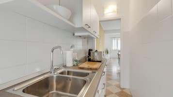 Une cuisine moderne avec des éviers en acier inoxydable, une planche à découper en bois et une casserole posée sur le plan de travail.