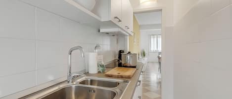A modern kitchen with stainless steel sinks, a wooden cutting board, and a pot on the counter.