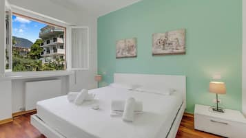 Une chambre à coucher avec un lit, deux tables de chevet, une fenêtre et des œuvres d’art accrochées au mur.