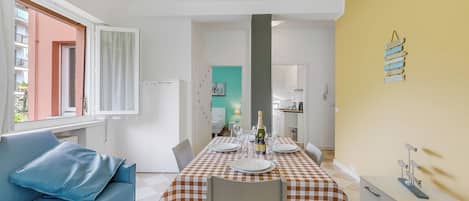 A dining area with a checkered tablecloth, a blue sofa, and a white cabinet.