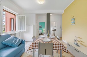 A dining area with a checkered tablecloth, a blue sofa, and a white cabinet.