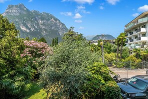 A hotel with a mountain view, lush greenery, and a parking area. - Blu Gem Modern (Riva del Garda)