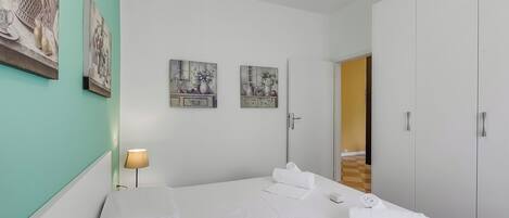 A hotel room with a bed, a nightstand, a lamp, and artwork on the walls.