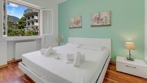 Een slaapkamer met een bed, twee nachtkastjes, een raam en kunst aan de muur.