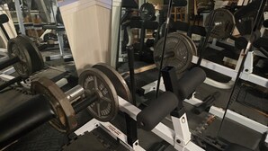 Uma academia com equipamentos de musculação, espelhos e uma parede de tijolos.