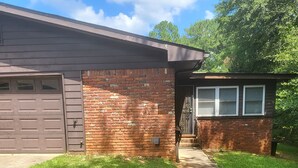 Uma casa com garagem, fachada de tijolos e um pequeno alpendre.