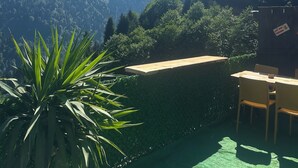 Terraza en la azotea con vistas a una montaña, una mesa de madera y sillas.
