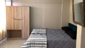 A bedroom with a bed, a wardrobe, a mirror, and a ceiling light. - Yoxall Overnight stays (Durban)