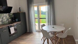 A modern kitchen with grey cabinets, a wooden countertop, and a dining area with a white table and chairs. - Pollmann Vacation Home - Quietly Located with a View of the Countryside (Höxter)