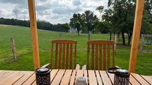 A wooden table with three lanterns and two chairs in an outdoor setting with a grassy field and trees in the background. - Pollmann Vacation Home - Quietly Located with a View of the Countryside (Höxter)
