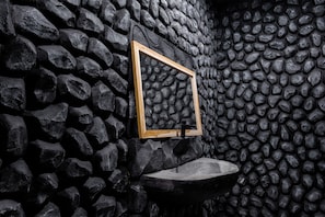 A stone wall with a wooden-framed mirror and a sink.