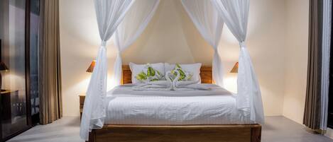 A four-poster canopy bed with white bedding and a wooden base, flanked by two bedside tables with lamps.