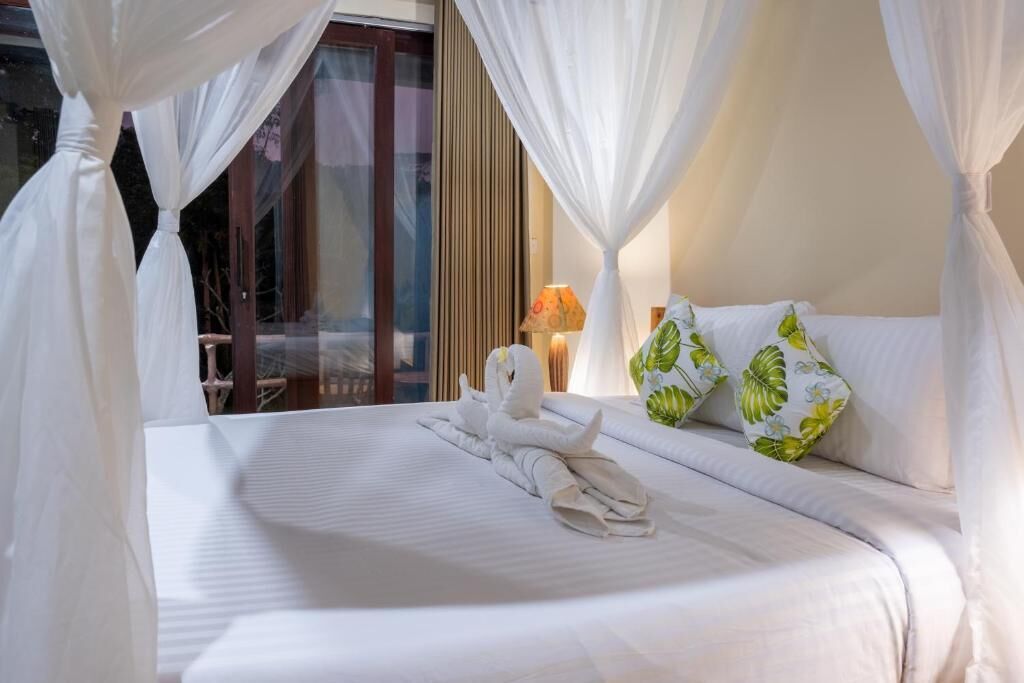 A bed with white bedding, a canopy, and decorative pillows.