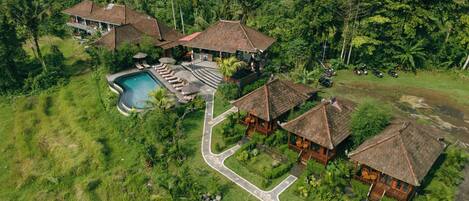 A resort with multiple bungalow-style buildings, a swimming pool, and lush greenery.