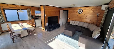 A modern interior with a dining area, a sofa, and a TV.