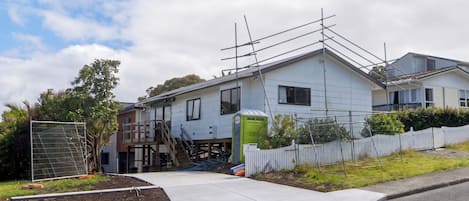 Un edificio residencial con un espacio exterior cubierto, un patio cercado y una escalera que lleva al segundo piso.