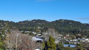 A residential area with houses on a hillside, surrounded by trees. - Sunny 3BDR Family Retreat in Leafy Glen Eden (Auckland)
