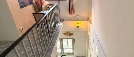 A staircase with a handrail, a wall-mounted light, and a window with blinds.