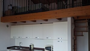Une cuisine avec des armoires blanches, un évier, un four à micro-ondes et un plafond en bois.