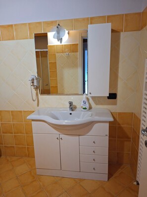 A bathroom with a white sink, a mirror, a shower, and a toilet. - Casa Manerba, near Romantica Beach (Lombardia)
