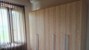 Une chambre à coucher avec un lit, une armoire en bois et un appareil de climatisation.