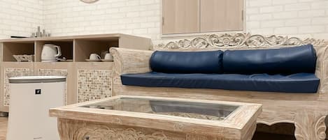 A living room with a sofa, a coffee table, a cabinet, and a refrigerator.
