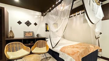 A room with a bed, two chairs, a small table, a decorative cabinet, and a canopy bed.