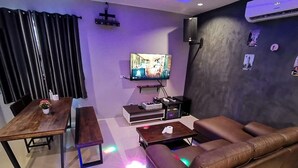 Ein Wohnzimmer mit einer Couch, einem Couchtisch, einem Fernseher auf einem Schrank, einem Holztisch und einer Bank.