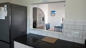 A kitchen with a black refrigerator, a mirror, and a sign that says 'bless our nest.'