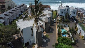 A residential area with modern buildings, a palm tree, and a view of the ocean.