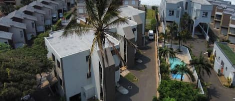 A residential area with modern buildings, a palm tree, and a view of the ocean.