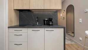 A modern kitchen with wooden cabinets, a marble countertop, and a coffee maker. - Beige Apartment By the River | 2 Balconies (Szczecin)