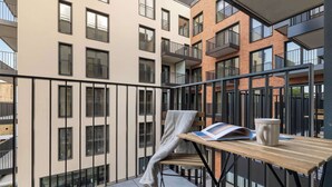 A balcony with a table, a chair, a book, and a mug. - Beige Apartment By the River | 2 Balconies (Szczecin)