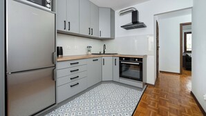 Eine moderne Küche mit grauen Schränken, einer eingebauten Mikrowelle, einem Edelstahl-Kühlschrank und einem gemusterten Boden.