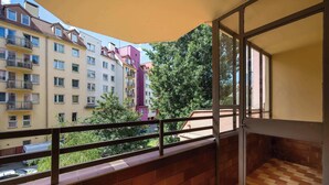Ein Balkon mit Blick auf mehrstöckige Gebäude, Holzboden und Metallgeländer.