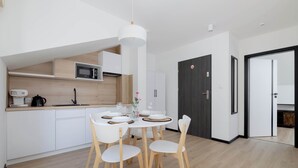 Une cuisine moderne avec des meubles blancs, un four à micro-ondes et un coin repas comprenant une table ronde et quatre chaises.