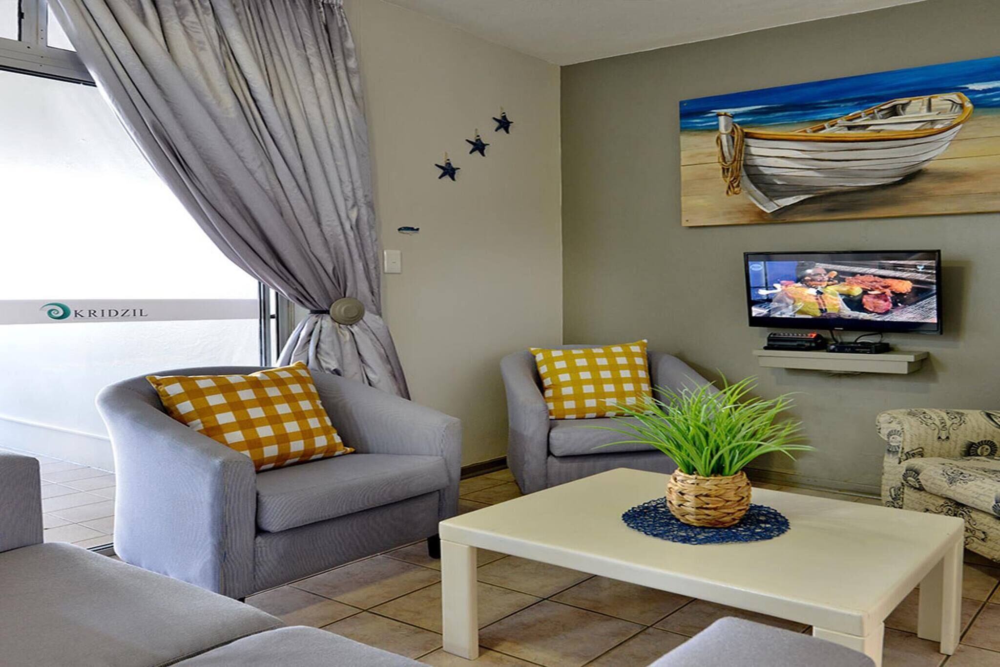 A living room with a sofa, armchair, coffee table, and a painting of a boat on the wall.