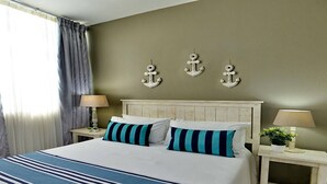 Een hotelkamer met een bed, twee nachtkastjes, een lamp op elk en drie decoratieve wandankers.