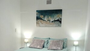 Un dormitorio con cama, dos lámparas de noche, un cuadro en la pared y una alfombra en el suelo.