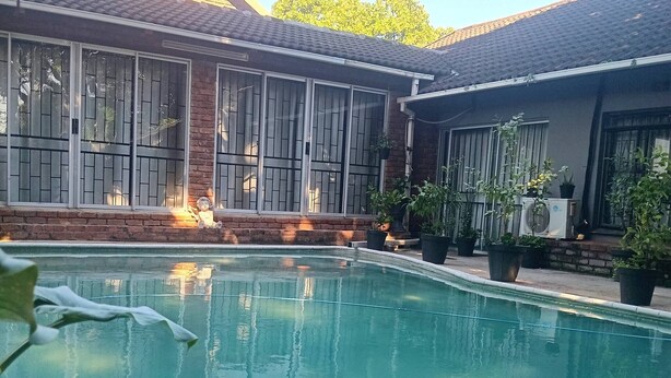 Une piscine dotée d’un toit carrelé, de plantes en pot et d’un mur en briques.