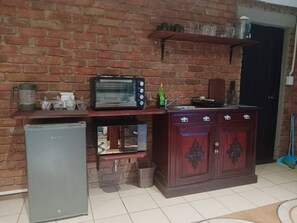 Eine Küche mit Backsteinwand, einem Toaster, einem Kühlschrank, einer Spüle und Holzschränken.