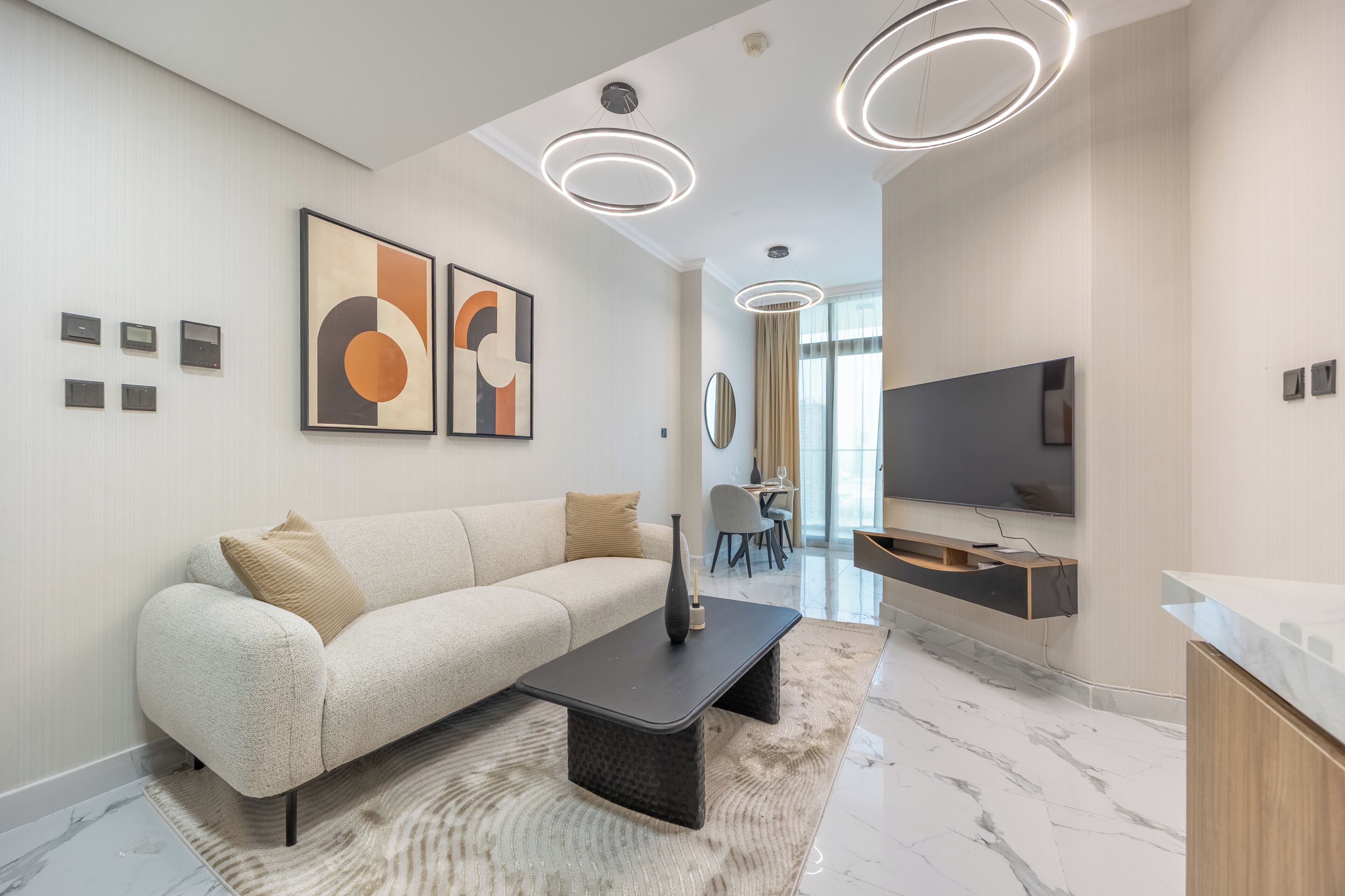 A modern living room with a sofa, a coffee table, a flat-screen TV, and abstract wall art.