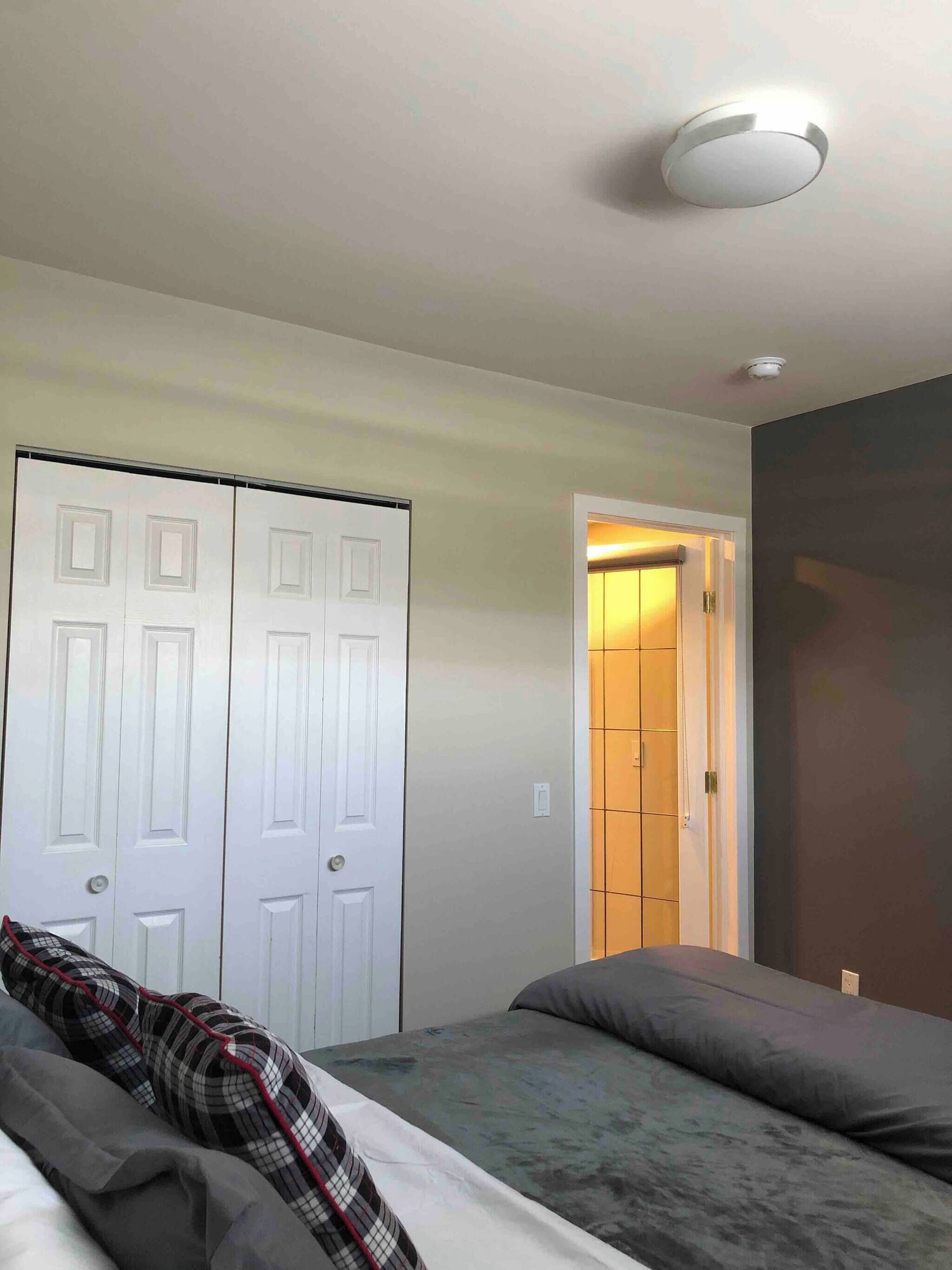 Une chambre à coucher comprenant un lit, une armoire et une porte donnant sur une autre pièce.